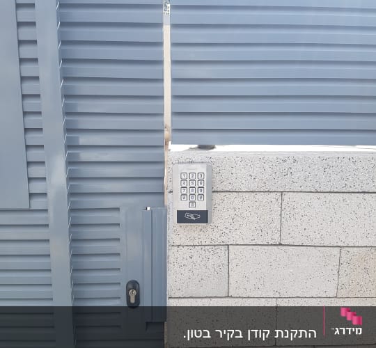 לוח מקשים של אינטרקום על קיר לבנים אפור